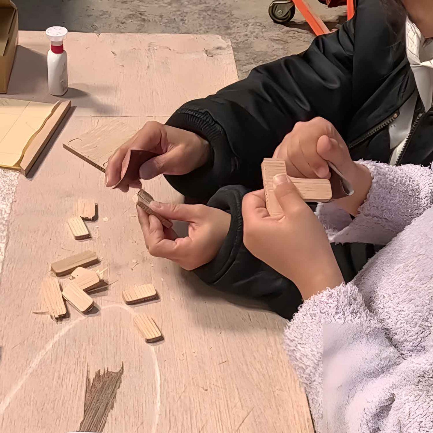 Scene from a woodworking event. Small children are assembling wooden parts by hand together with adults, grandfathers, and grandmothers. Toys made from natural materials that are safe for children to play with. SOZOZAKKA. そうぞうざっか.